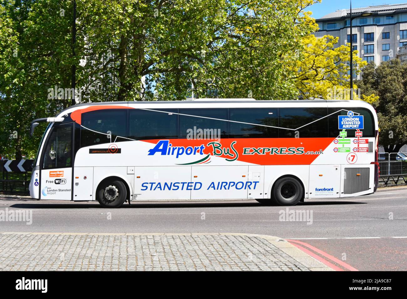 Vista lateral del conductor y gráfico publicitario en el servicio de autobús Easy Bus Stansted Airport Express en Park Lane con salida en Londres, Inglaterra, Reino Unido Foto de stock