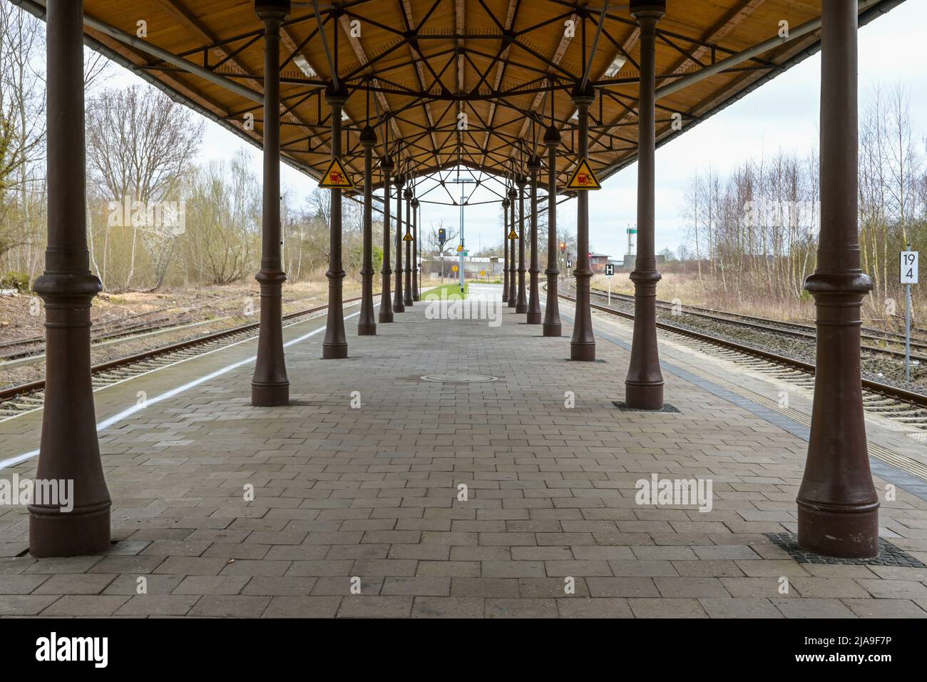 Plataforma cubierta con columnas antiguas, andamios metálicos y techo de madera entre las vías del ferrocarril en la estación de Schonberg, Mecklemburgo, Alemania Foto de stock