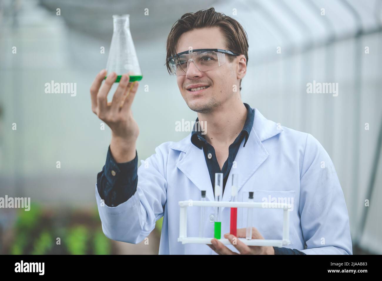 bio científico en agricultura granja feliz sonrisa mirada en la nueva fórmula química extracto de muestra de concepto de granja de plantas. Foto de stock