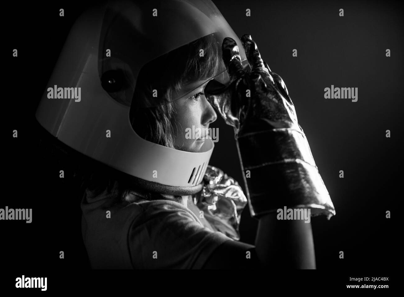 Retrato de niño divertido con casco de astronauta niño pequeño lindo  astronauta en traje espacial sosteniendo casco sobre fondo negro