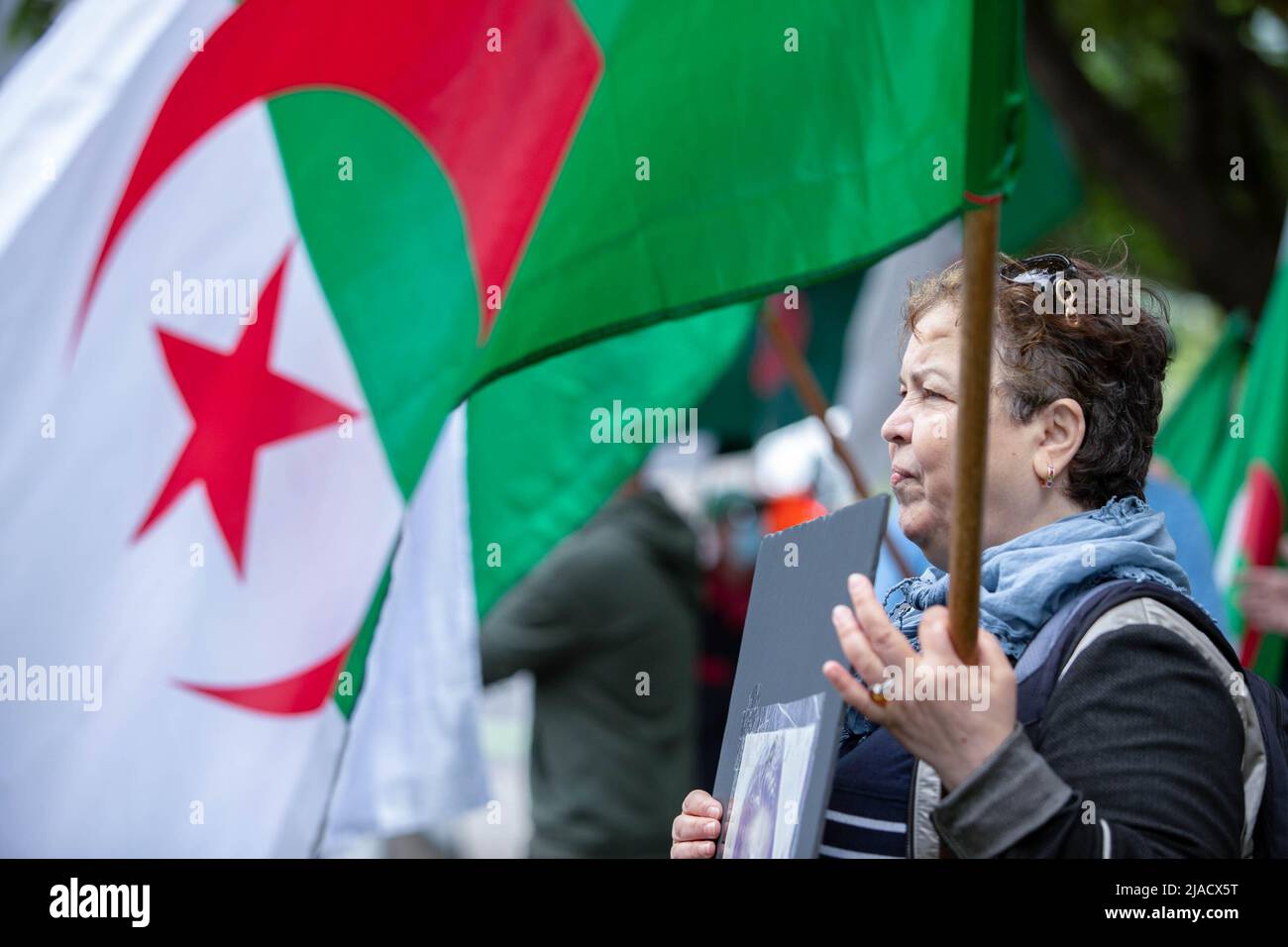 Leila Cheurfi sostiene la bandera argelina mientras canta los nombres de sus seres queridos secuestrados durante la protesta. Cuatro años después de la diáspora argelina, el movimiento Hirak sigue luchando por la democracia en Montreal. Organizado por Tous unis pour notre Algerie, cientos de manifestantes se reunieron frente al Consulado de Argelia para exigir la retirada de los actuales líderes políticos, encabezados por el presidente Abdelmadjid Tebboune. Citando la corrupción crónica y la falta de resoluciones previsables, los manifestantes llamaron al gobierno un gobierno mafioso. Foto de stock