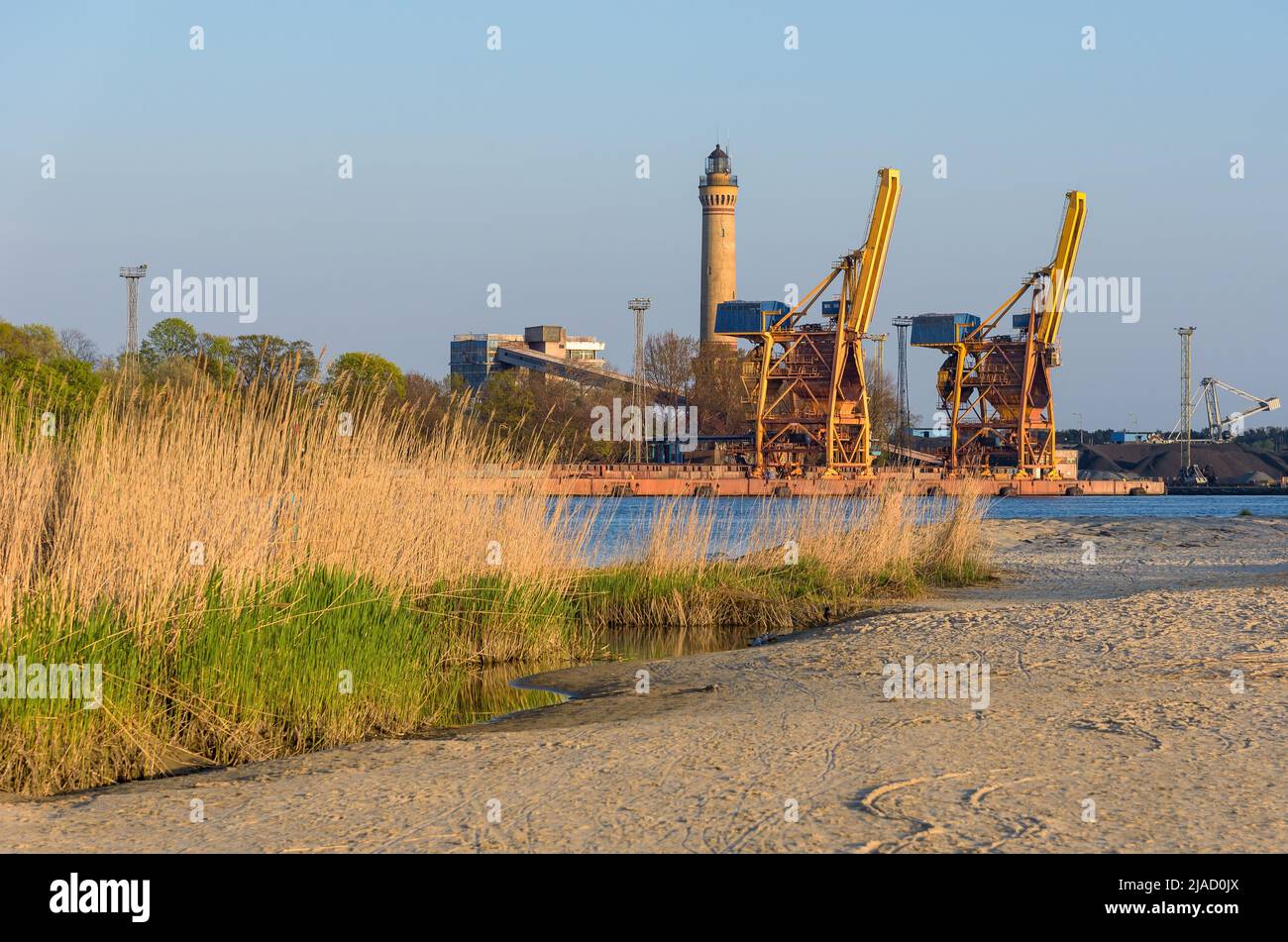 Grúas portuarias y un faro en Swinoujscie en Polonia en una tarde soleada Foto de stock