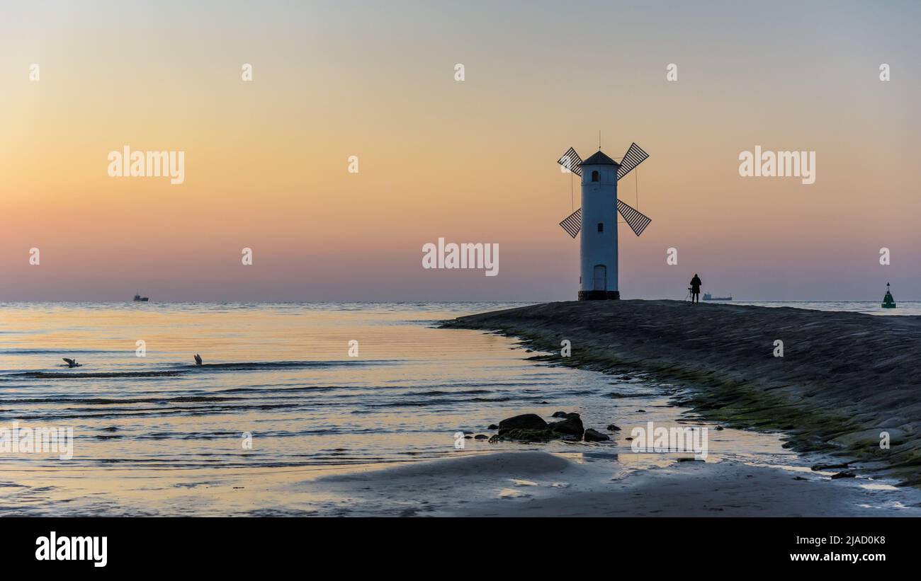 El fotógrafo toma una foto del Stawa Mlyny, un faro en forma de molino de viento como símbolo oficial de Swinoujscie al atardecer Foto de stock