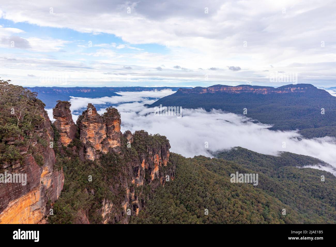 Tres Hermanas en la zona Patrimonio de la Humanidad de las Montañas Azules y Mount Solitary dentro del valle Jamison con inversión de nubes, NSW, Australia Foto de stock