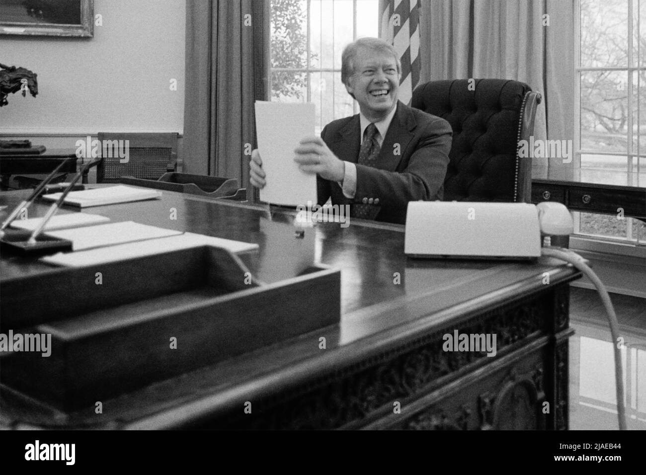 El Presidente de los Estados Unidos, Jimmy Carter, está trabajando en un discurso para la televisión en la Oficina Oval de la Casa Blanca, Washington, D.C., el 2 de febrero de 1977. (EE. UU.) Foto de stock