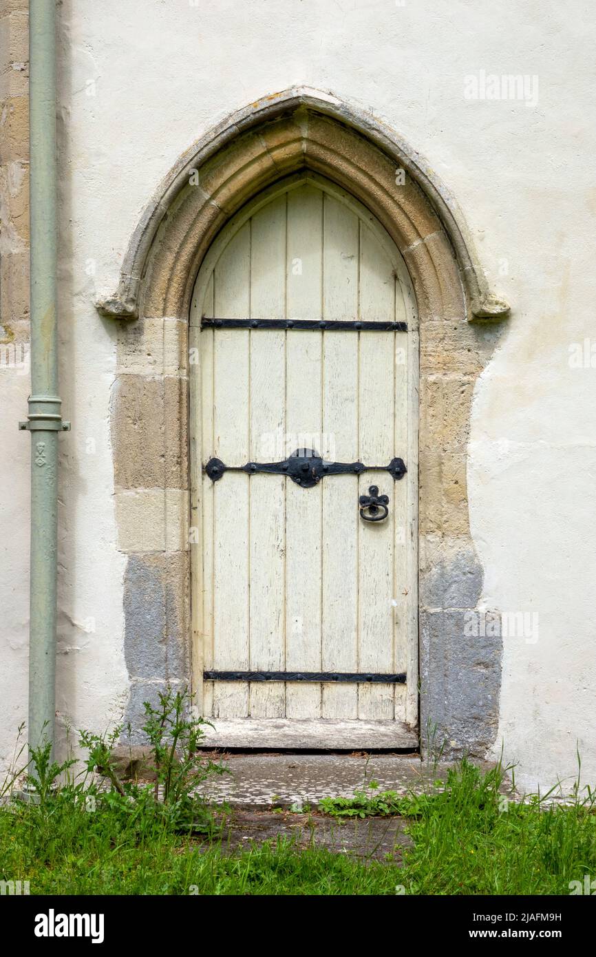 Puerta arqueada pequeña con puerta de madera, en la Iglesia de Todos los Santos, Brandeston, Suffolk Foto de stock
