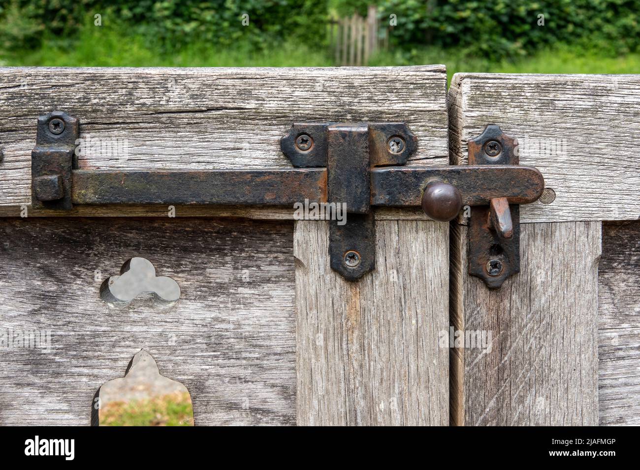 Pestillo de la compuerta de hierro en puertas de madera descoloridas y deterioradas Foto de stock