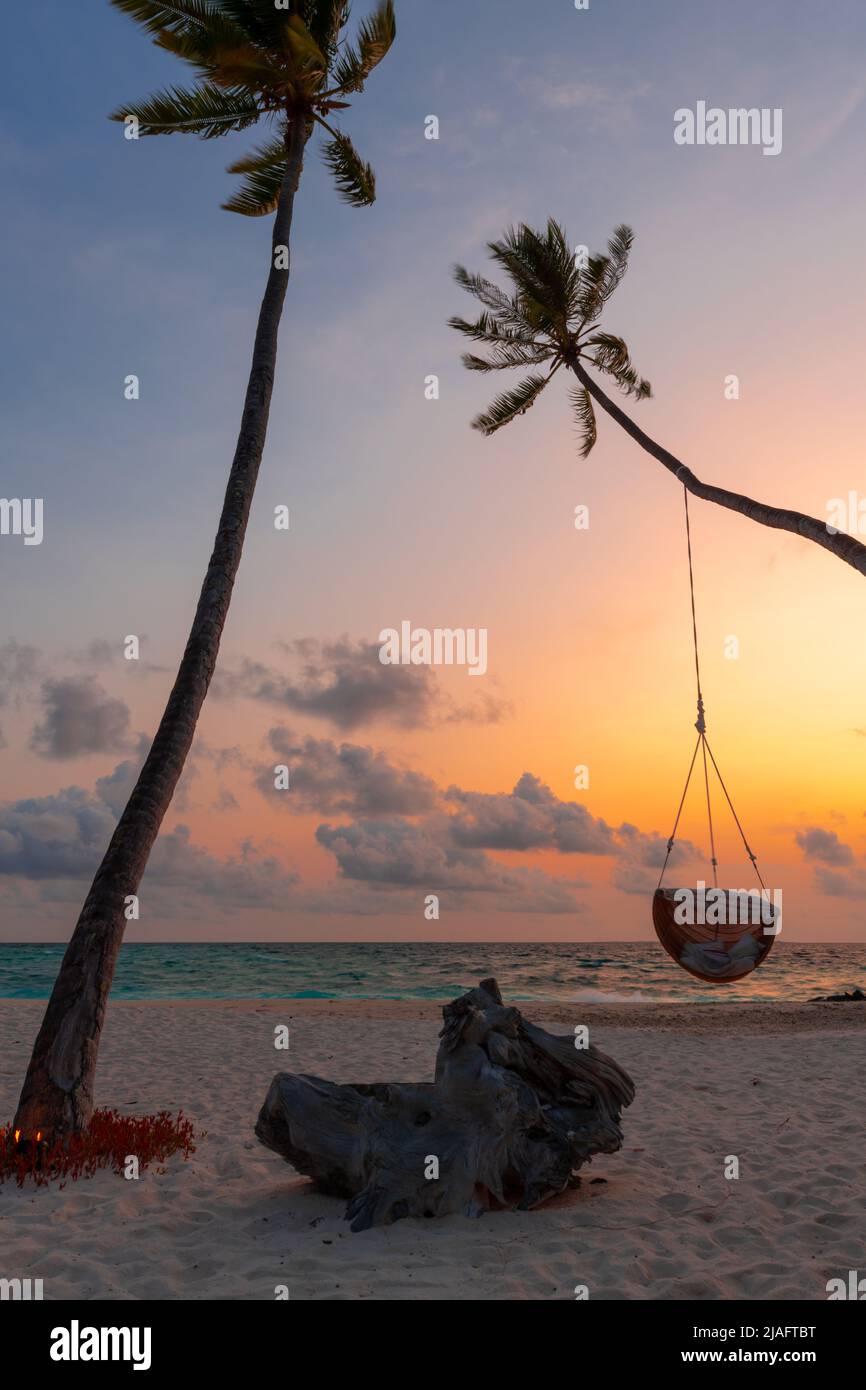 Vista de una colorida puesta de sol en la playa con palmeras en primer plano. Concepto de escapada tropical. Foto de stock