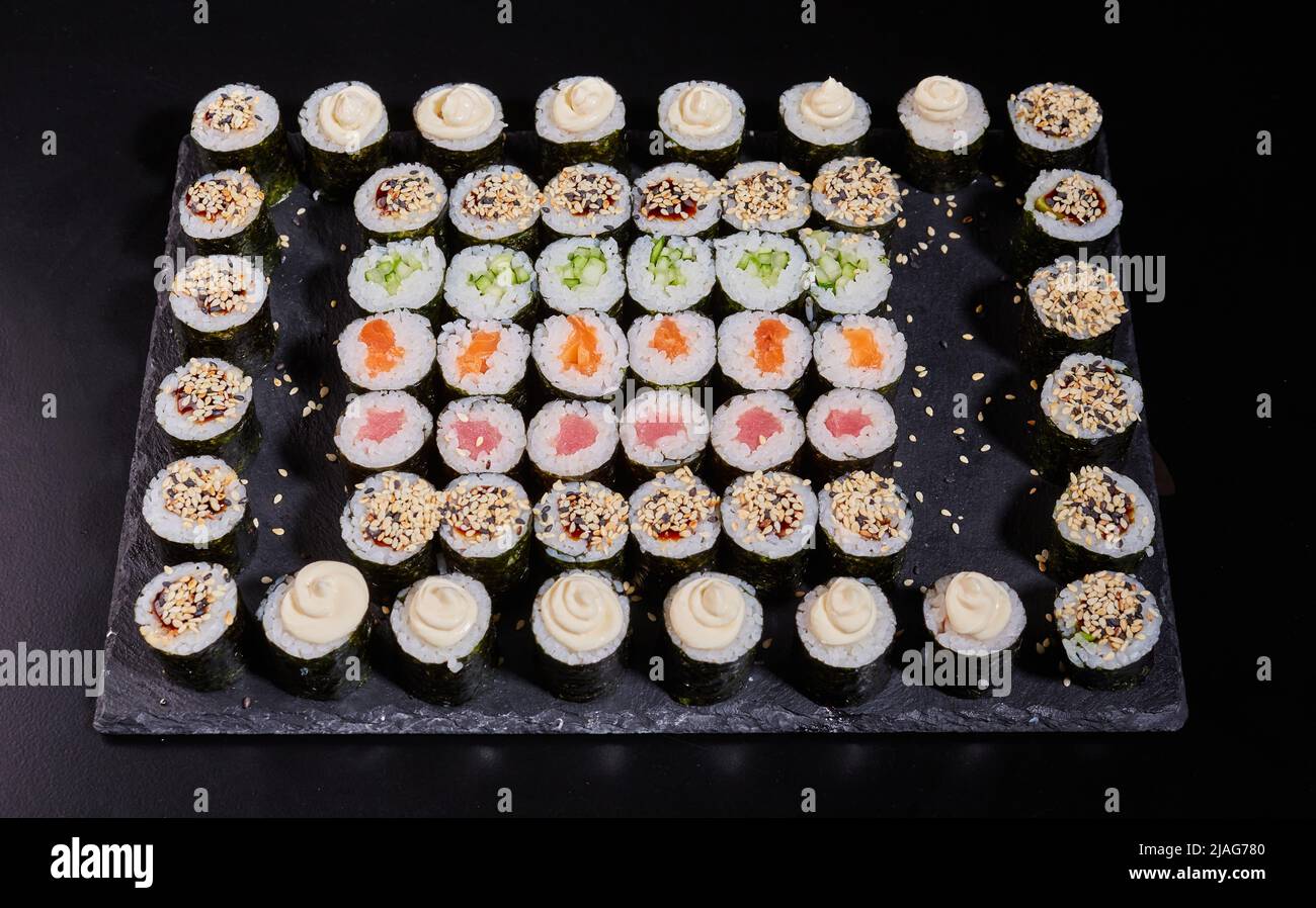 Juego de sushi japonés. Diferentes tipos de rollos de maki sobre un plato sobre un fondo de piedra. Foto de stock