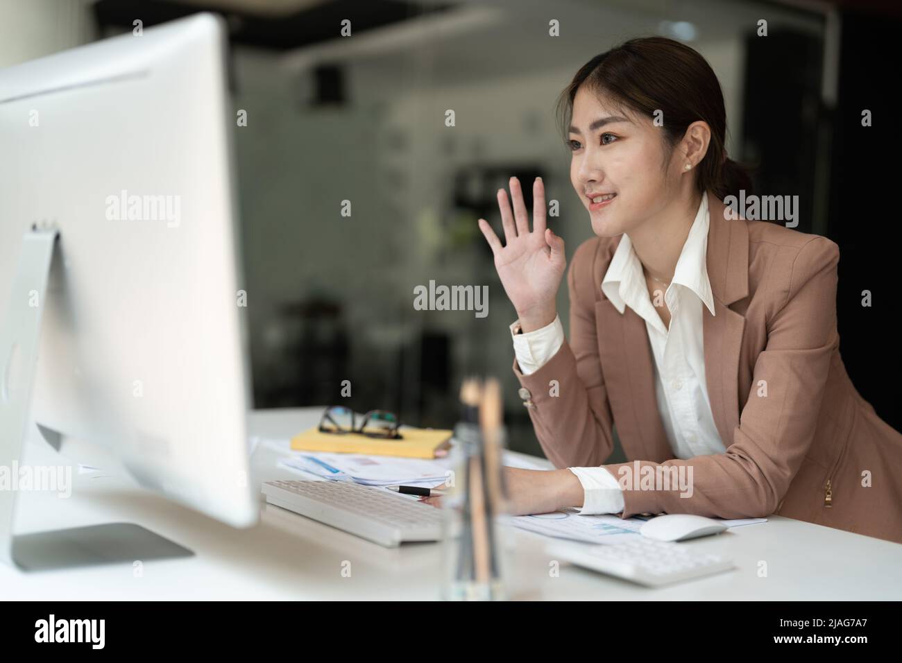 Una joven empresaria asiática trabaja en casa y una videoconferencia virtual con colegas, gente de negocios, trabajo en línea, videollamada debido a la actividad social Foto de stock
