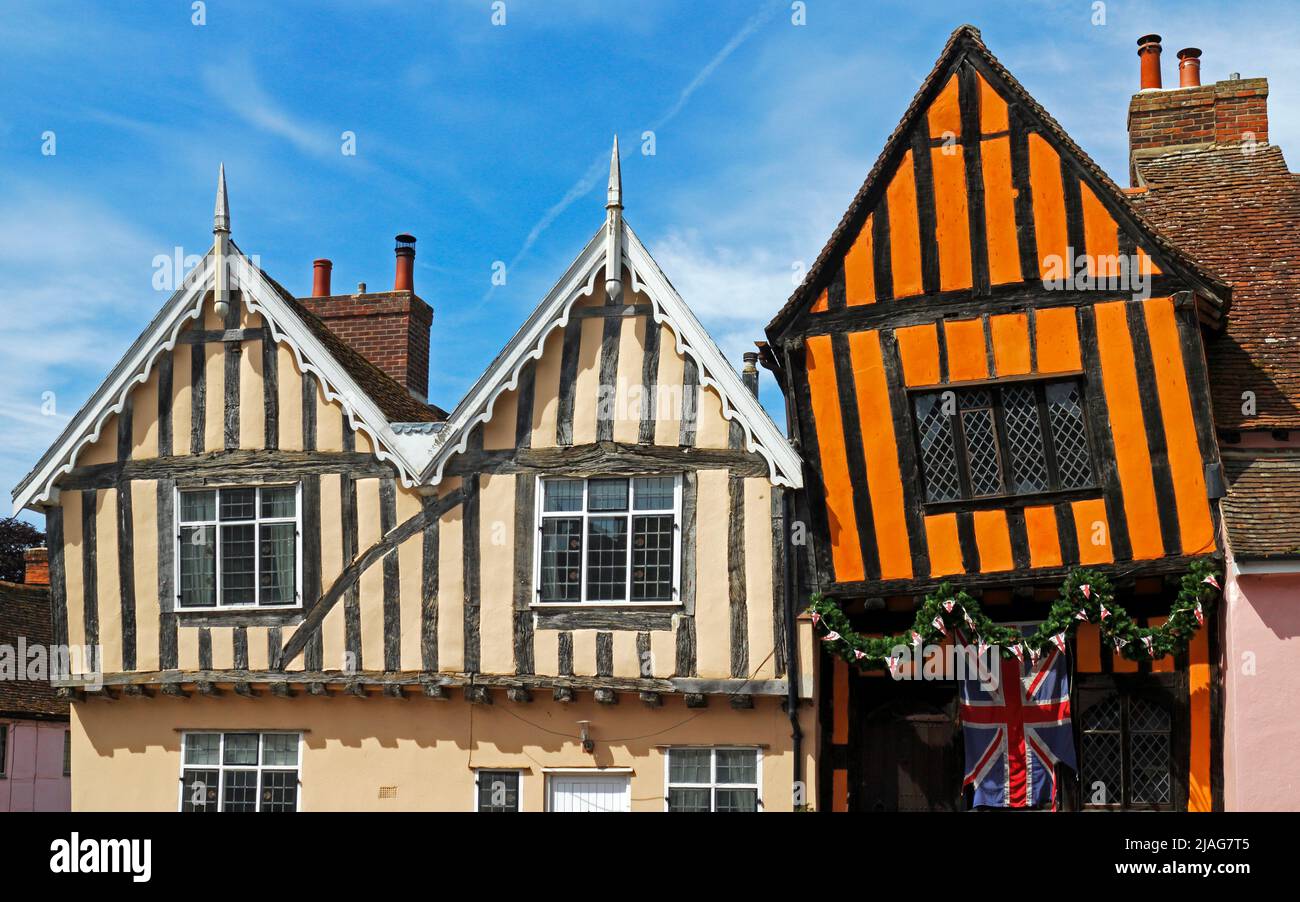 Una vista de dos edificios medievales con entramado de madera incluyendo la casa de color naranja Crooked en la calle High Street en Lavenham, Suffolk, Inglaterra, Reino Unido. Foto de stock