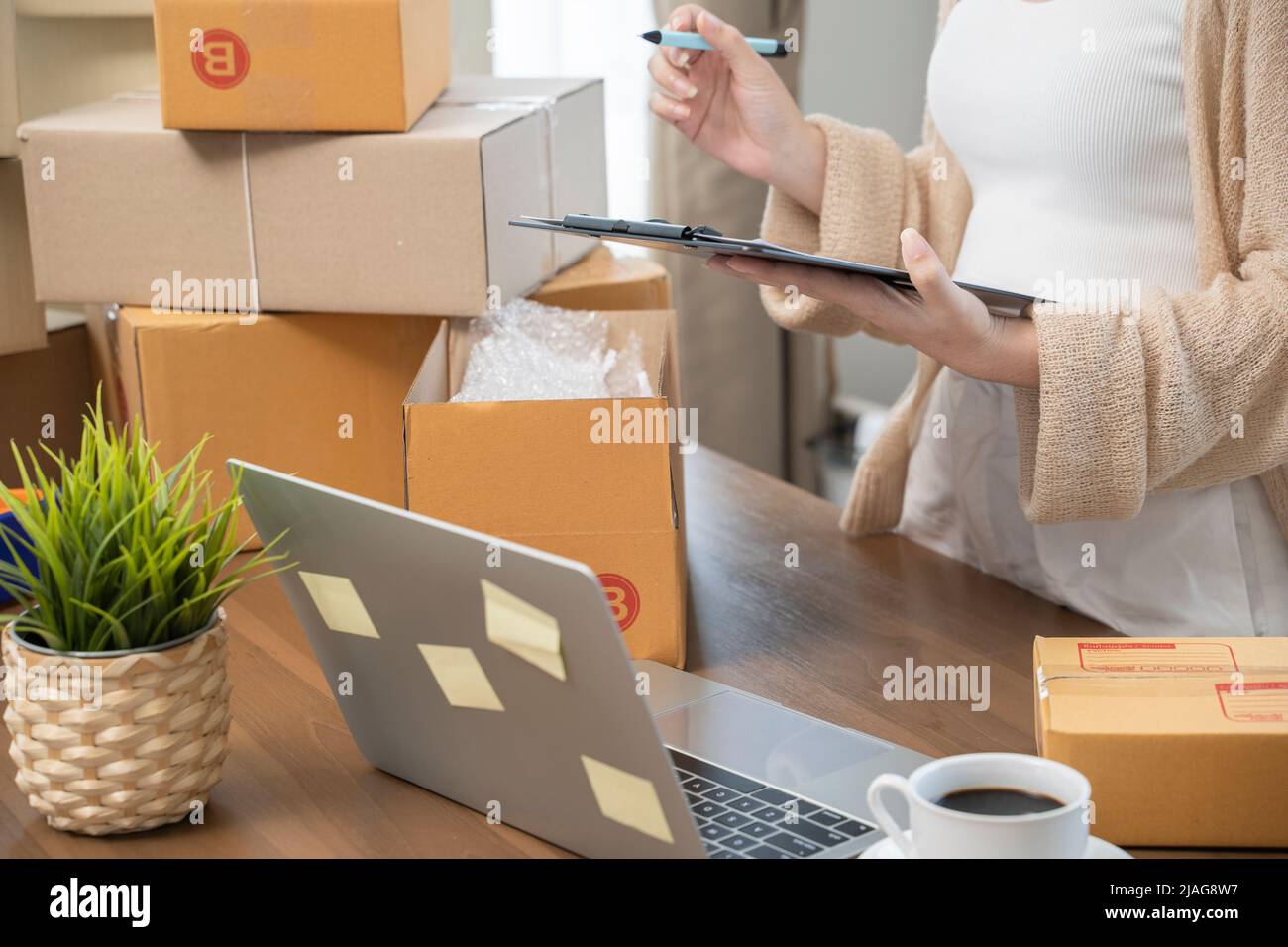 Mujer asiática empaquetando en cajas para trabajar en el hogar Propietarios de pequeñas empresas o Emprendedores de negocios pequeños del inicio que trabajan en cajas de envío de la comercialización en línea. Foto de stock