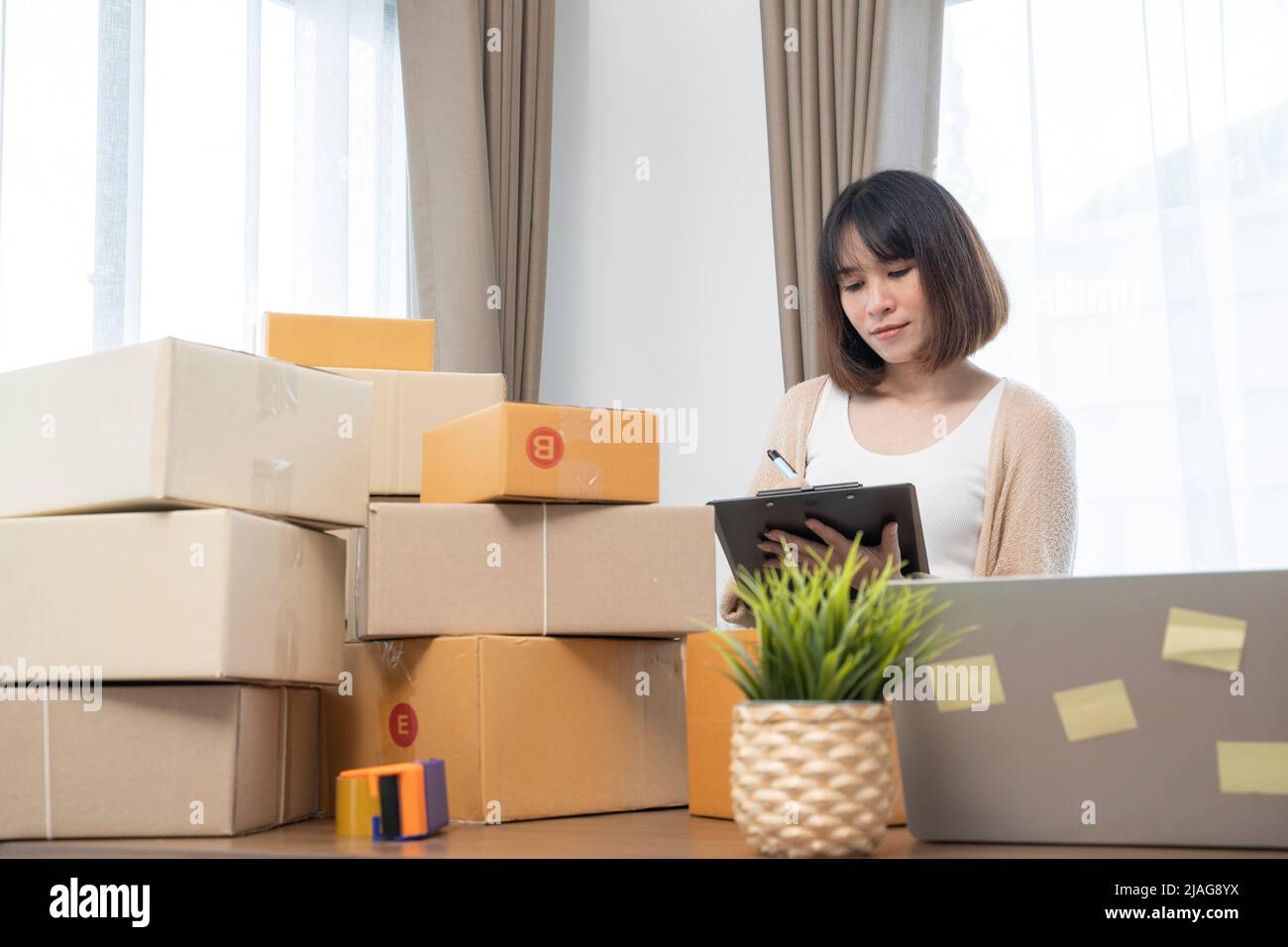 Las mujeres asiáticas cuentan cajas antes de enviar a los clientes, el trabajo desde casa, los propietarios de pequeñas empresas o los empresarios de pequeñas empresas que acaba de empezar a trabajar Foto de stock