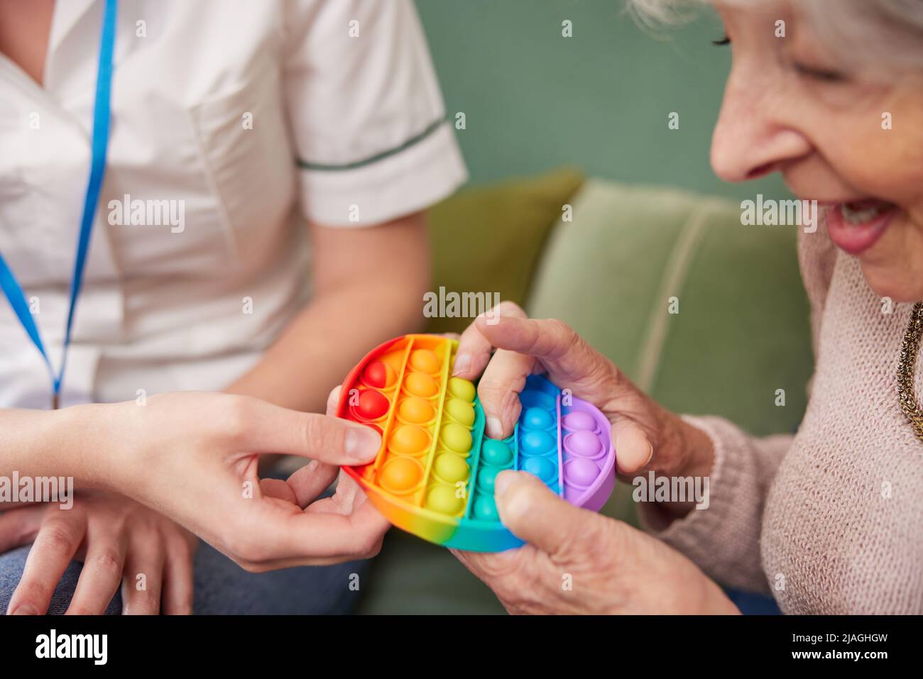 Fisioterapeuta Femenina Conseguir a la Mujer Senior a Squeeze Rubber Ball en casa Foto de stock