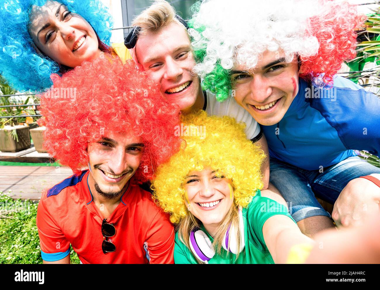 Aficionados al fútbol amigos tomando selfie después de un partido de la copa de fútbol colgando juntos - grupo de jóvenes con camisetas multicolores Foto de stock