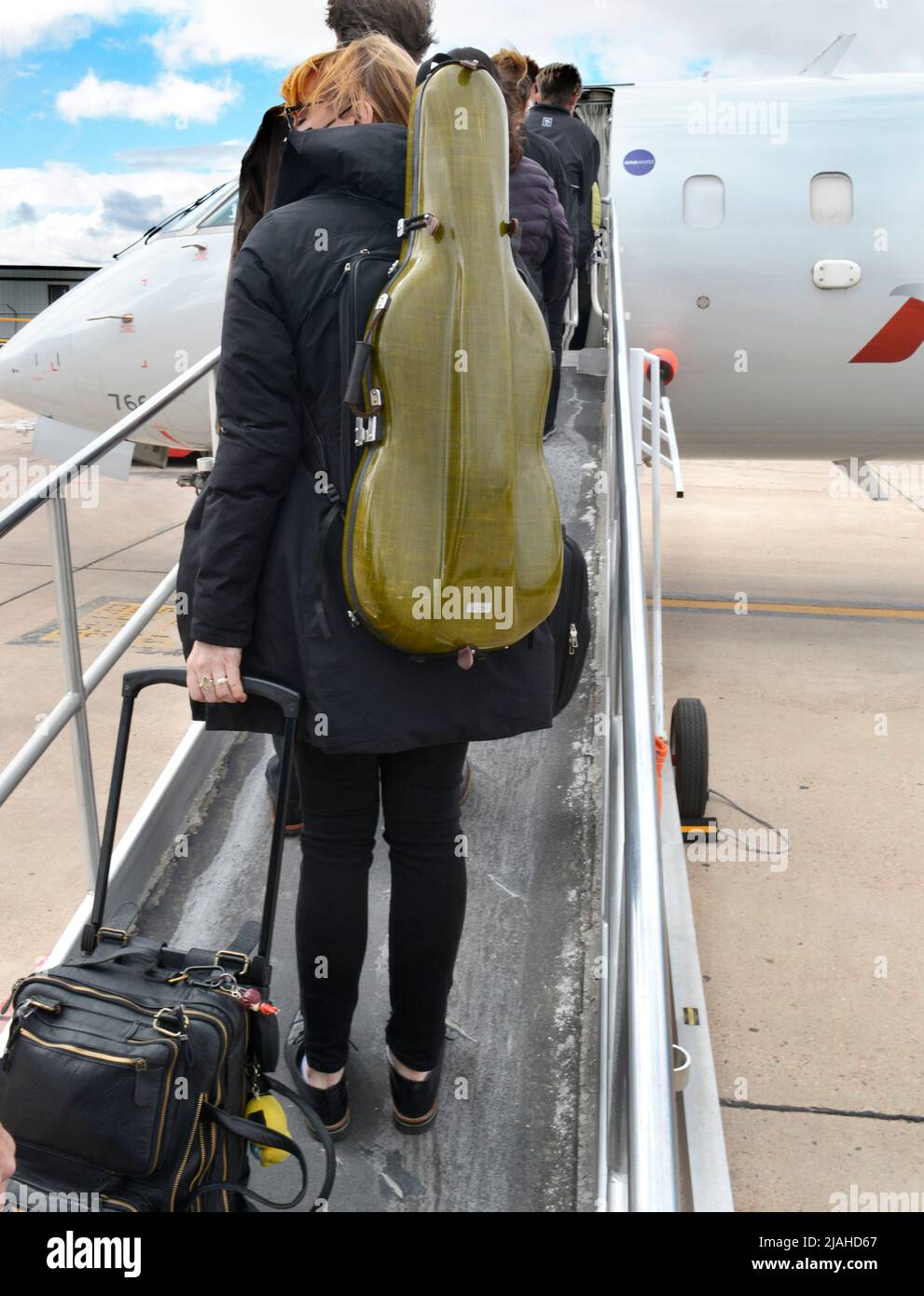 Un pasajero que lleva un instrumento musical como equipaje de mano aborda  un avión American Eagle en el Aeropuerto Municipal de Santa Fe en Santa Fe,  Nuevo México Fotografía de stock -