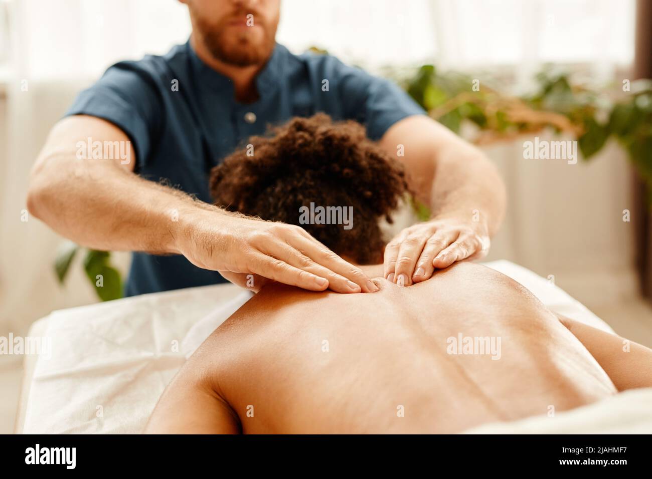 Tonos cálidos el primer plano del hombre masajea la espalda y los hombros  de una mujer joven que disfruta de una sesión de SPA Fotografía de stock -  Alamy
