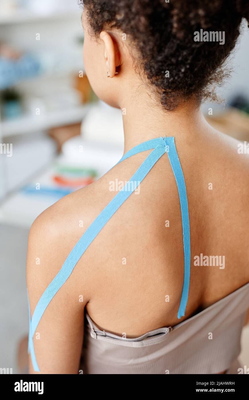 primer plano vertical de una mujer joven con cinta fisiológica en el hombro en terapia de rehabilitación Foto de stock