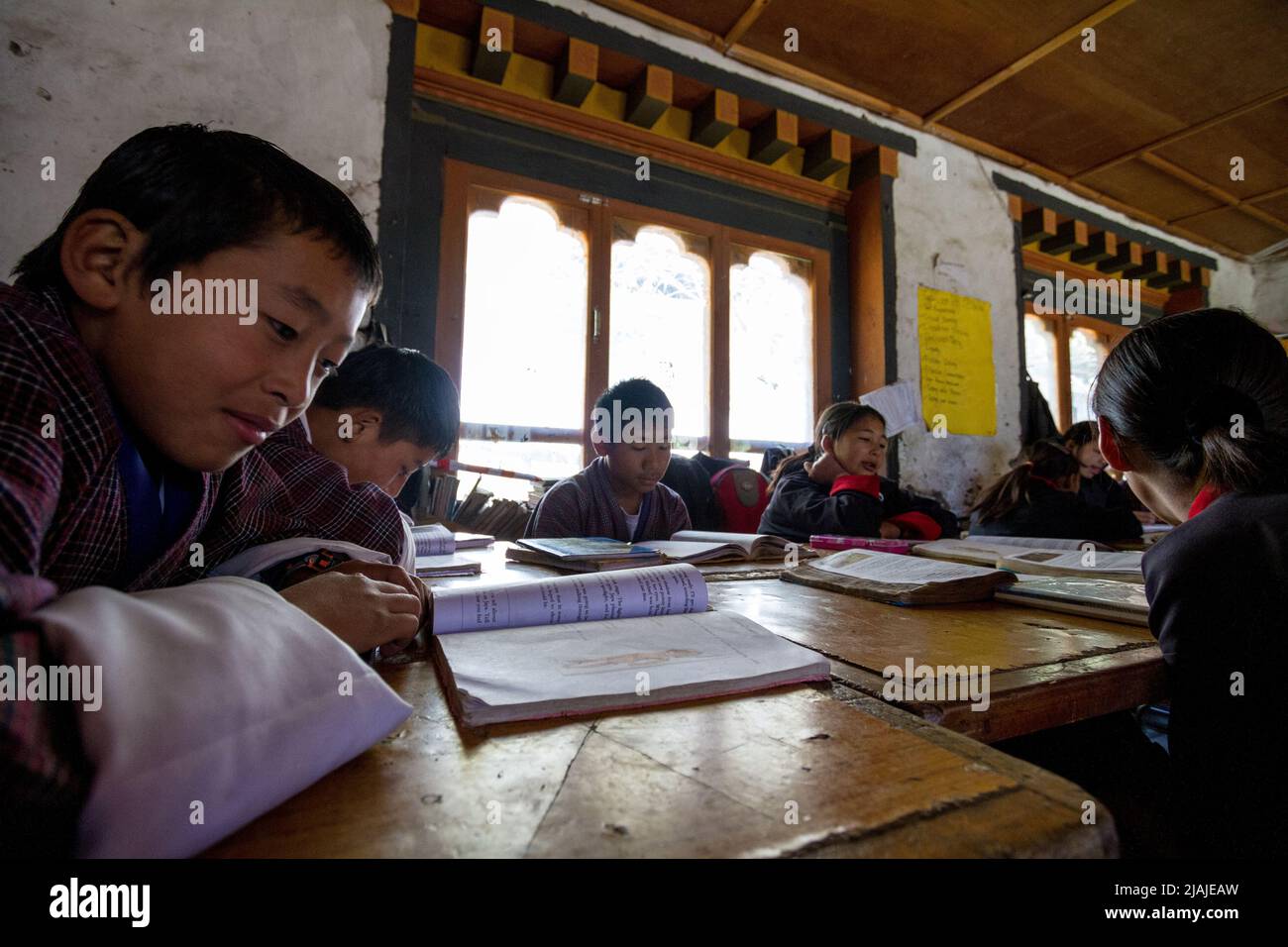 Los niños están sentados en escritorios de madera en una zona rural de Bhután Escuela de grado mientras aprende varios temas en Bután Foto de stock