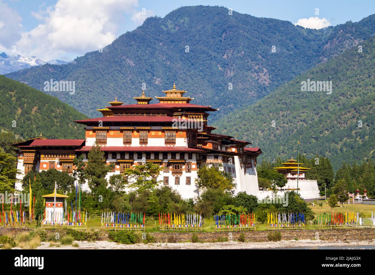 Los Punakha Dzong es visto a través de la mo Chhu River en el centro de Bután mientras banderas de oración Budista cercano flutter Foto de stock