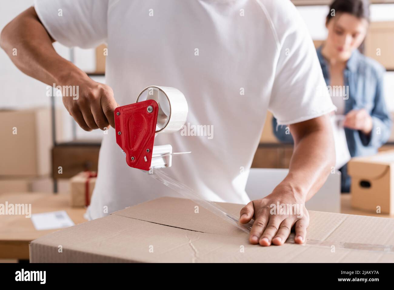 Vendedor afroamericano envasando caja de cartón con cinta adhesiva en tienda web en línea Foto de stock