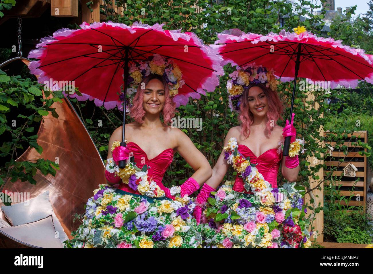 Dos modelos con vestidos de flores y guirnaldas y con coloridas sombrillas en el Salón de Flor Chelsea de RHS. Foto de stock