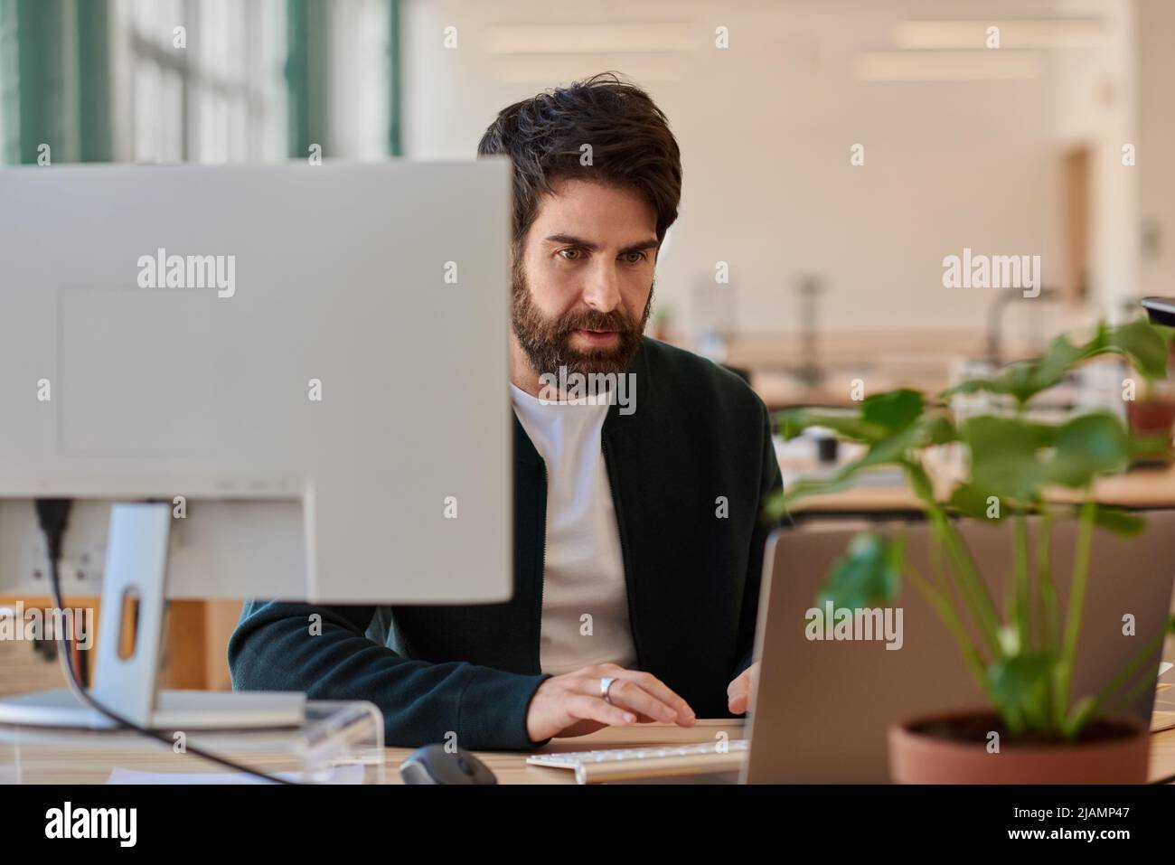 Un joven hombre de negocios centrado en trabajar con un portátil en su escritorio de oficina Foto de stock