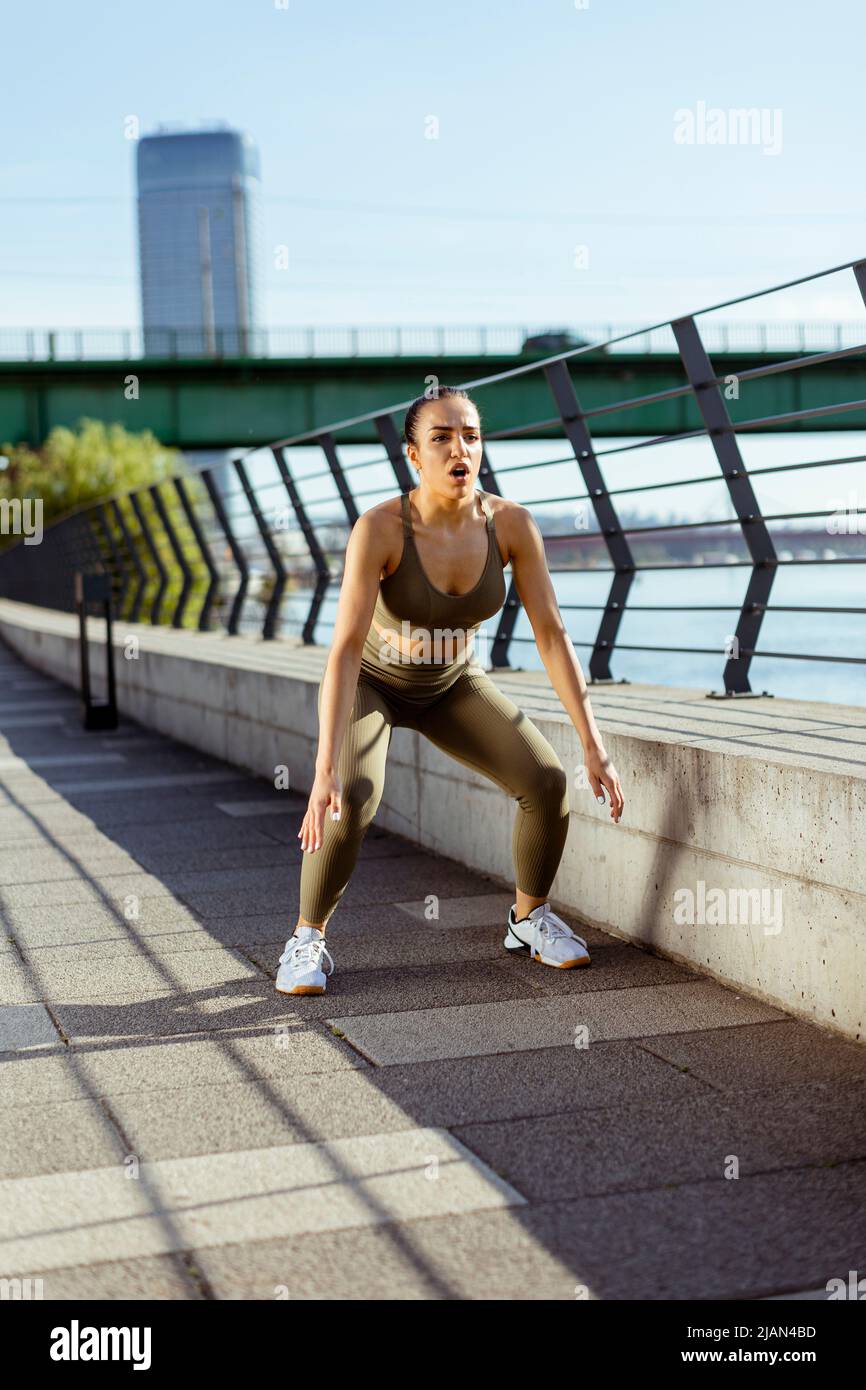 Una mujer joven y bonita en ropa deportiva que se extiende por un paseo del  río Fotografía de stock - Alamy