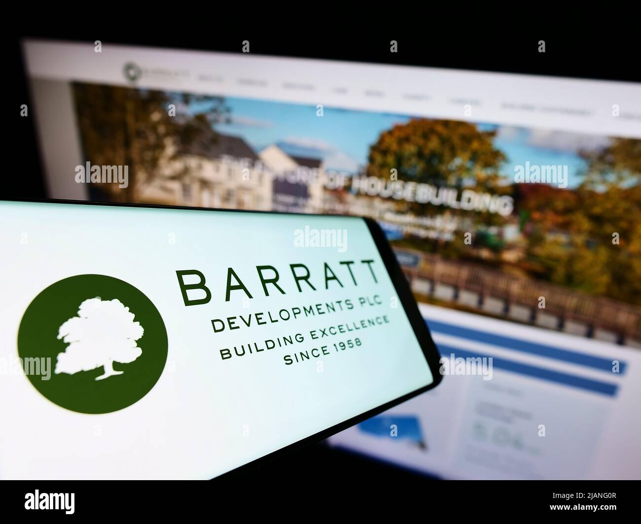 Teléfono móvil con el logotipo de la empresa inmobiliaria Barratt Desarrollos plc en la pantalla frente al sitio web de negocios. Enfoque en la parte central izquierda de la pantalla del teléfono. Foto de stock