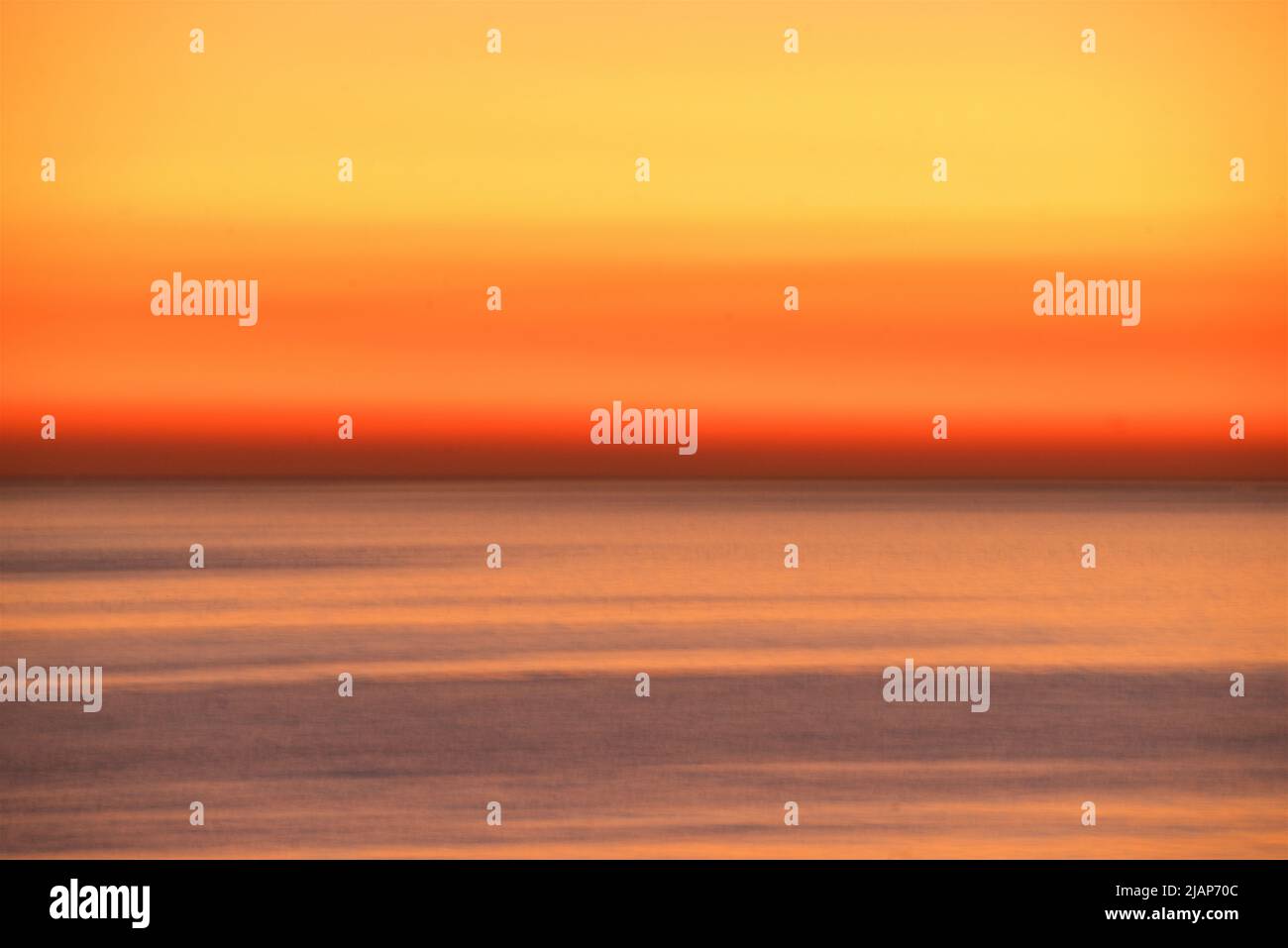 Detalles abstractos de ondas borrosas en movimiento en un mar tranquilo con un horizonte dorado al atardecer más allá. Canal en inglés, Reino Unido. Foto de stock