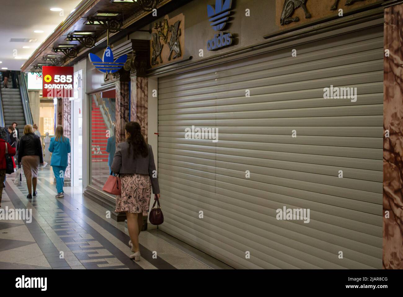 Una mujer pasa por una boutique Adidas cerrada en un centro comercial de  Moscú. Adidas anunció anteriormente que estaba suspendiendo todas las ventas  minoristas y de comercio electrónico en Rusia. (Foto de
