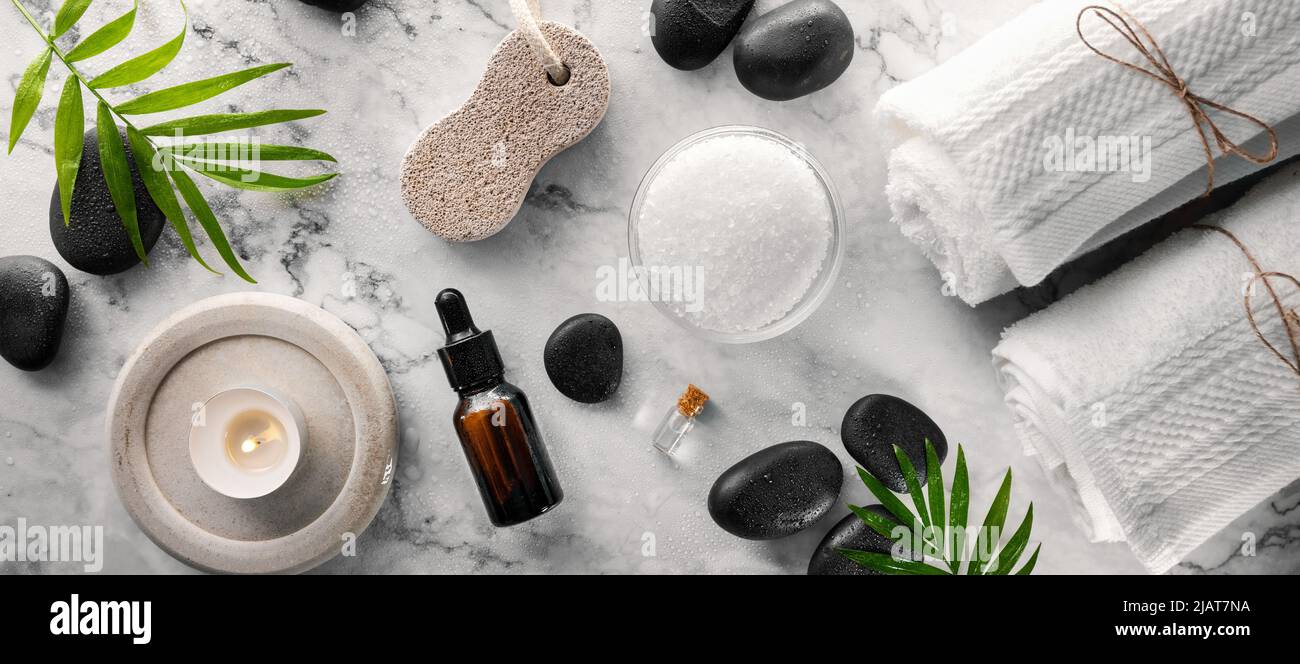 artículos de tratamiento de spa: piedras de masaje calientes con sal y aceites sobre mesa de mármol. banner de vista superior Foto de stock