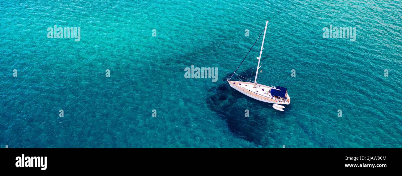 Vista aérea de un velero anclado en el mar esmeralda. Vista aérea de un barco. Deportes acuáticos al aire libre, vela. Vista aérea de anclar yate en wa abierta Foto de stock
