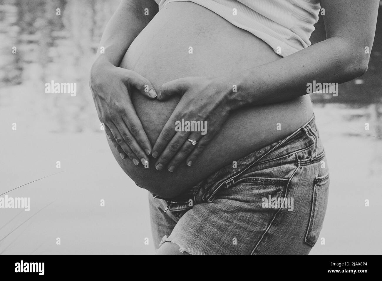 Vientre y manos de la madre embarazada en forma de corazón Foto de stock