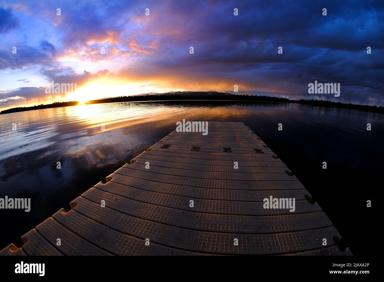 Lago al atardecer o al amanecer con nubes y reflejos del cielo que reflejan los colores del agua Foto de stock