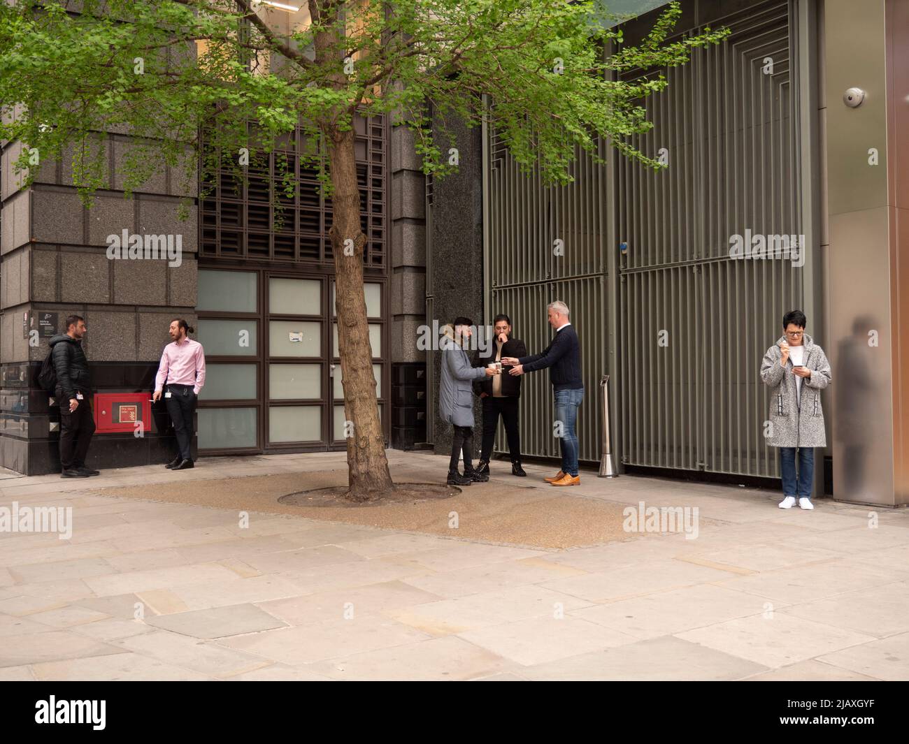 Grupo de fumadores, fumar cigarrillos fuera de la oficina en el centro de Londres, durante el descanso Foto de stock