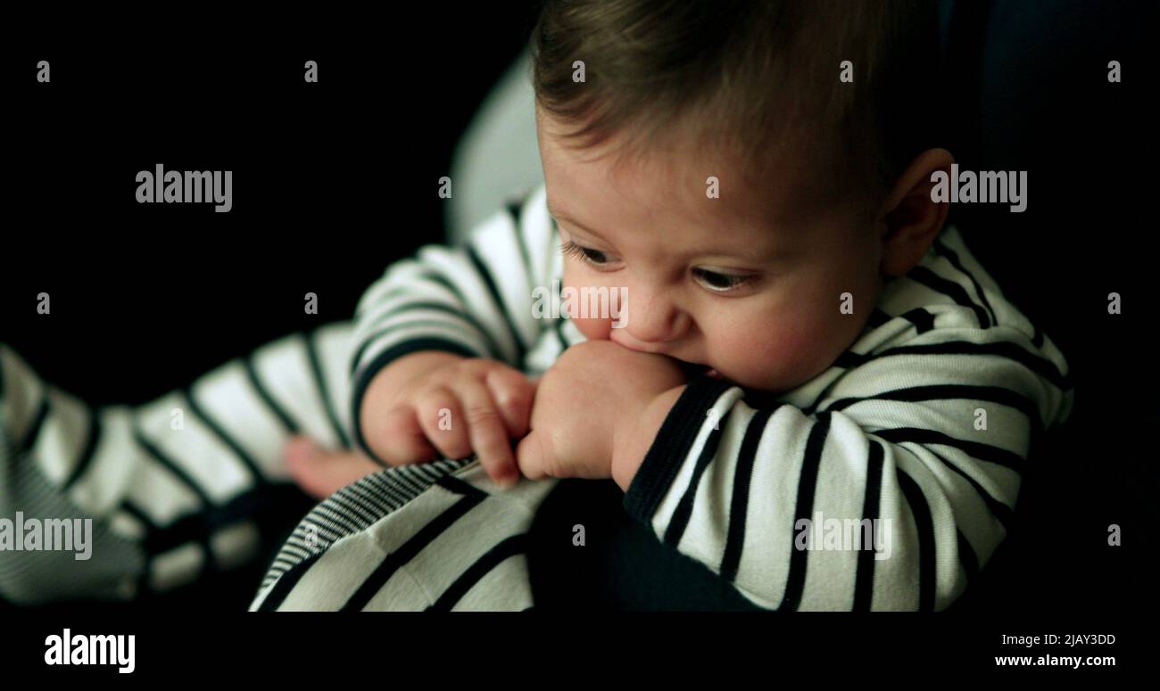 Lindo bebé usando pijama poniendo los pies en la boca. Adorable bebé siendo lindo Foto de stock