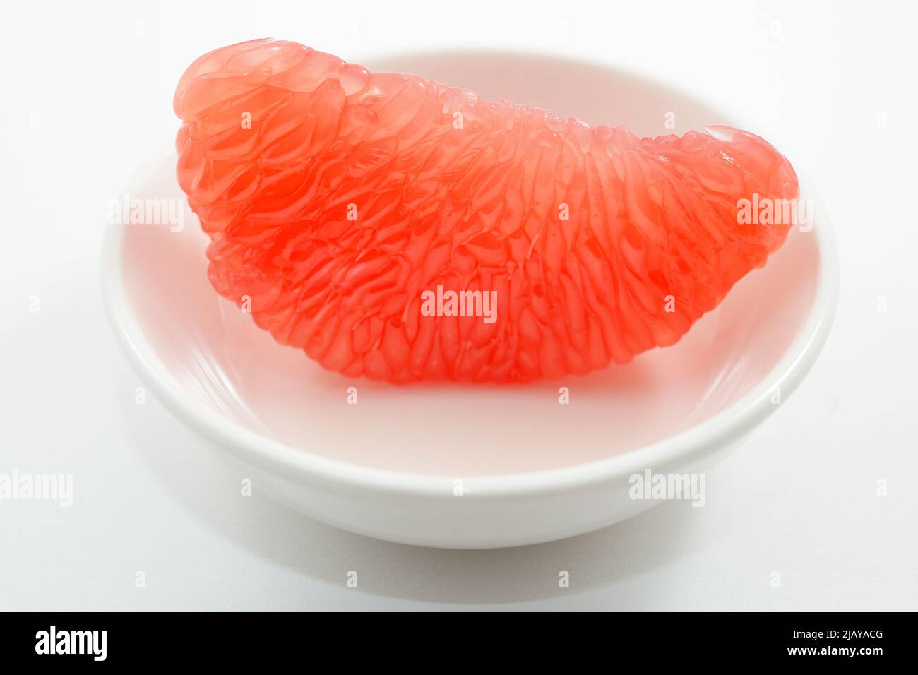 jugosa rodaja de pomelo rojo sobre platillo blanco Foto de stock