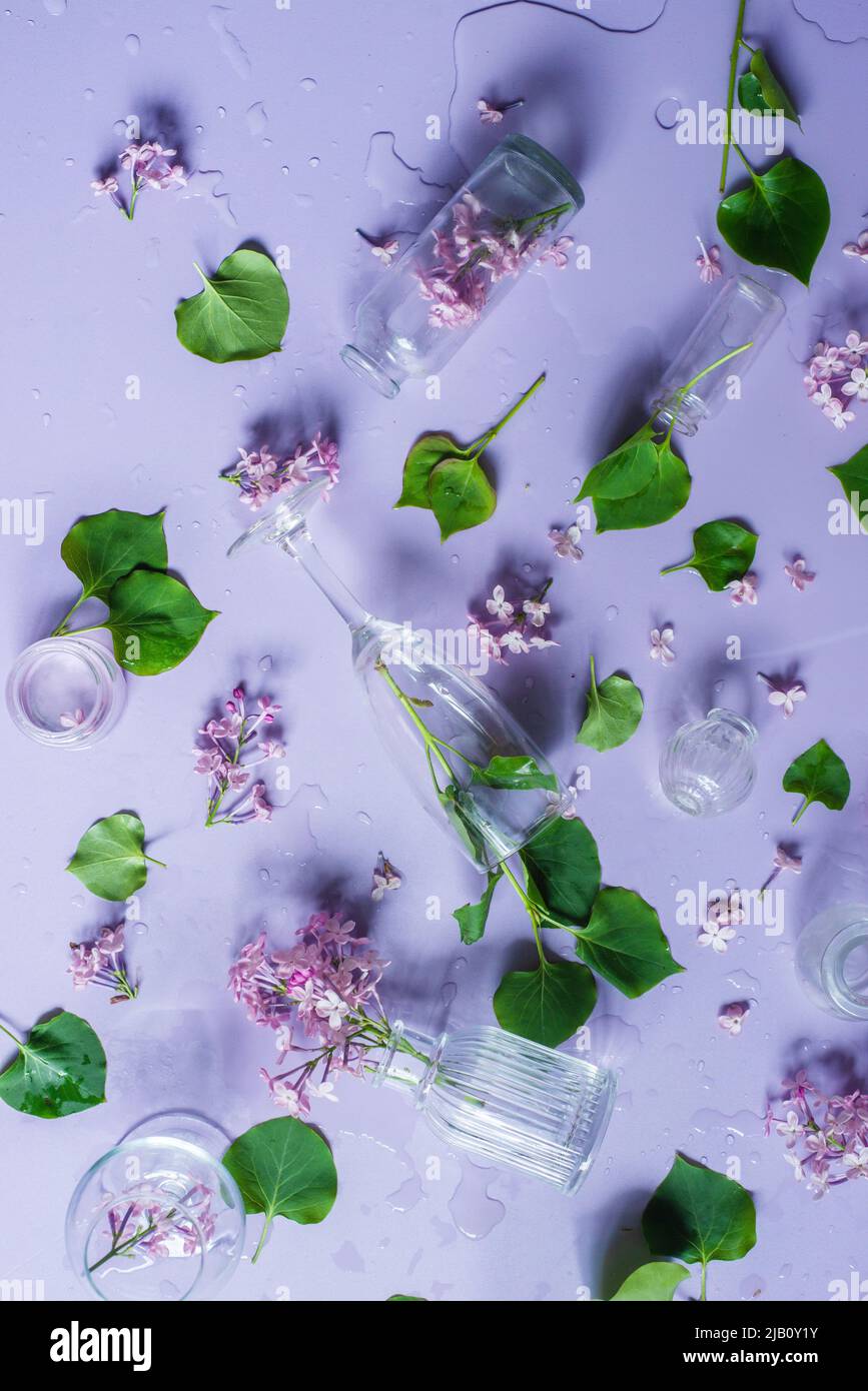 Botellas de vidrio con flores lilas, colores pastel plana, violeta todavía vida desde arriba Foto de stock