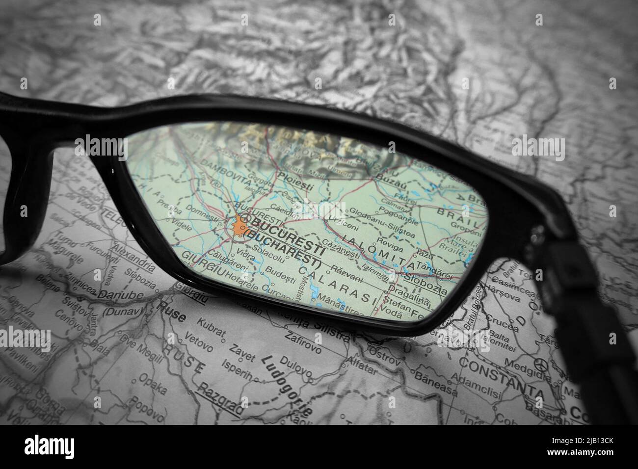 Una imagen ilustrativa creativa que muestra el país de Bucarest en un mapa a través de la lente de las gafas de lectura. La palabra Bucarest en color Foto de stock