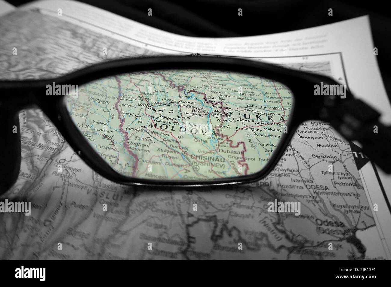 Una imagen ilustrativa creativa que muestra el país de Moldavia en un mapa a través de la lente de las gafas de lectura. El área alrededor de la palabra Moldavia en color Foto de stock