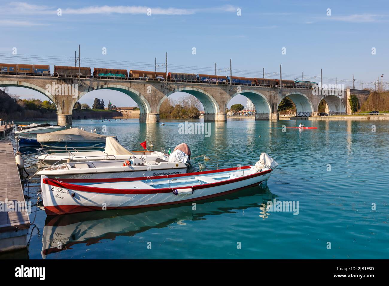 Peschiera del Garda, Italia - 25 de marzo de 2022: Tren de carga sobre un puente sobre el río Mincio en Peschiera del Garda, Italia. Foto de stock