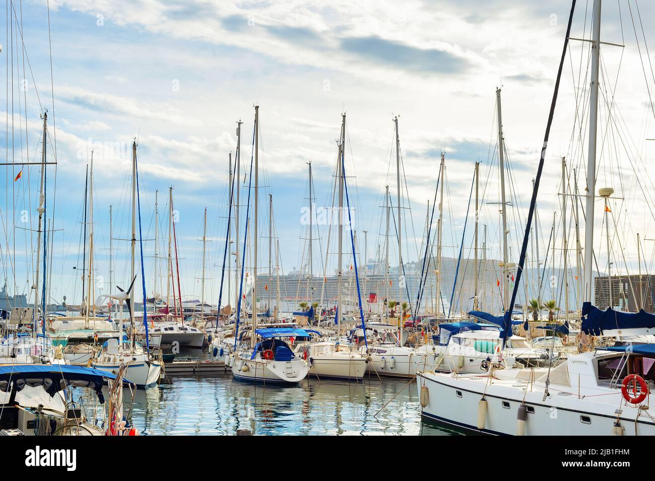Puerto deportivo con yates de lujo amarrados, crucero en el fondo, cielo nublado. Sanremo, Italia Foto de stock
