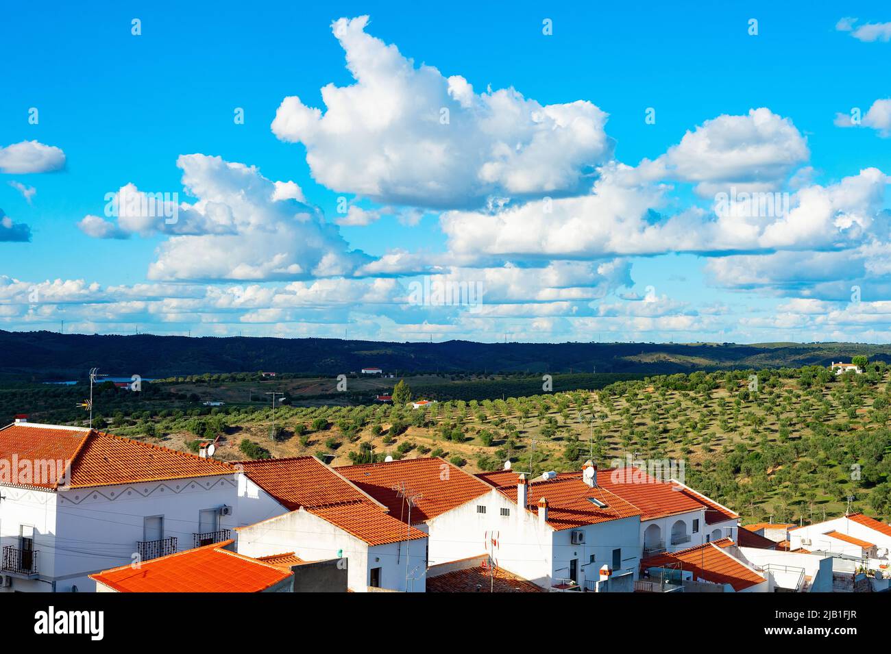 Paisaje natural con vista al pueblo y a los jardines de olivo, montañas y nubes, España Foto de stock