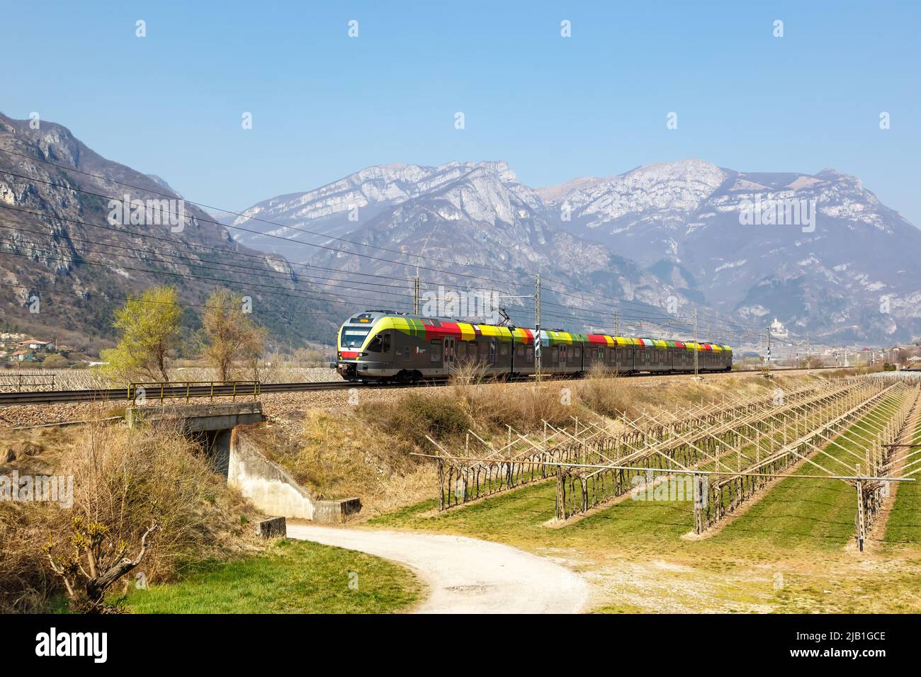 AVIO, Italia - 25 de marzo de 2022: Stadler COQUETEA el tren regional de Trenitalia en el ferrocarril de Brenner cerca de Avio, Italia. Foto de stock