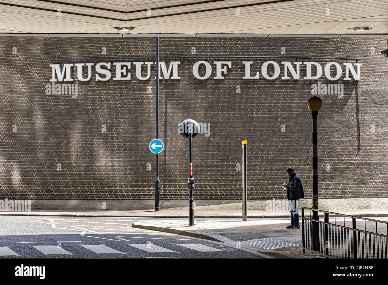 Un hombre de pie mirando su teléfono cerca del Museo de Londres, en la Rotunda Londres, EC2 Foto de stock