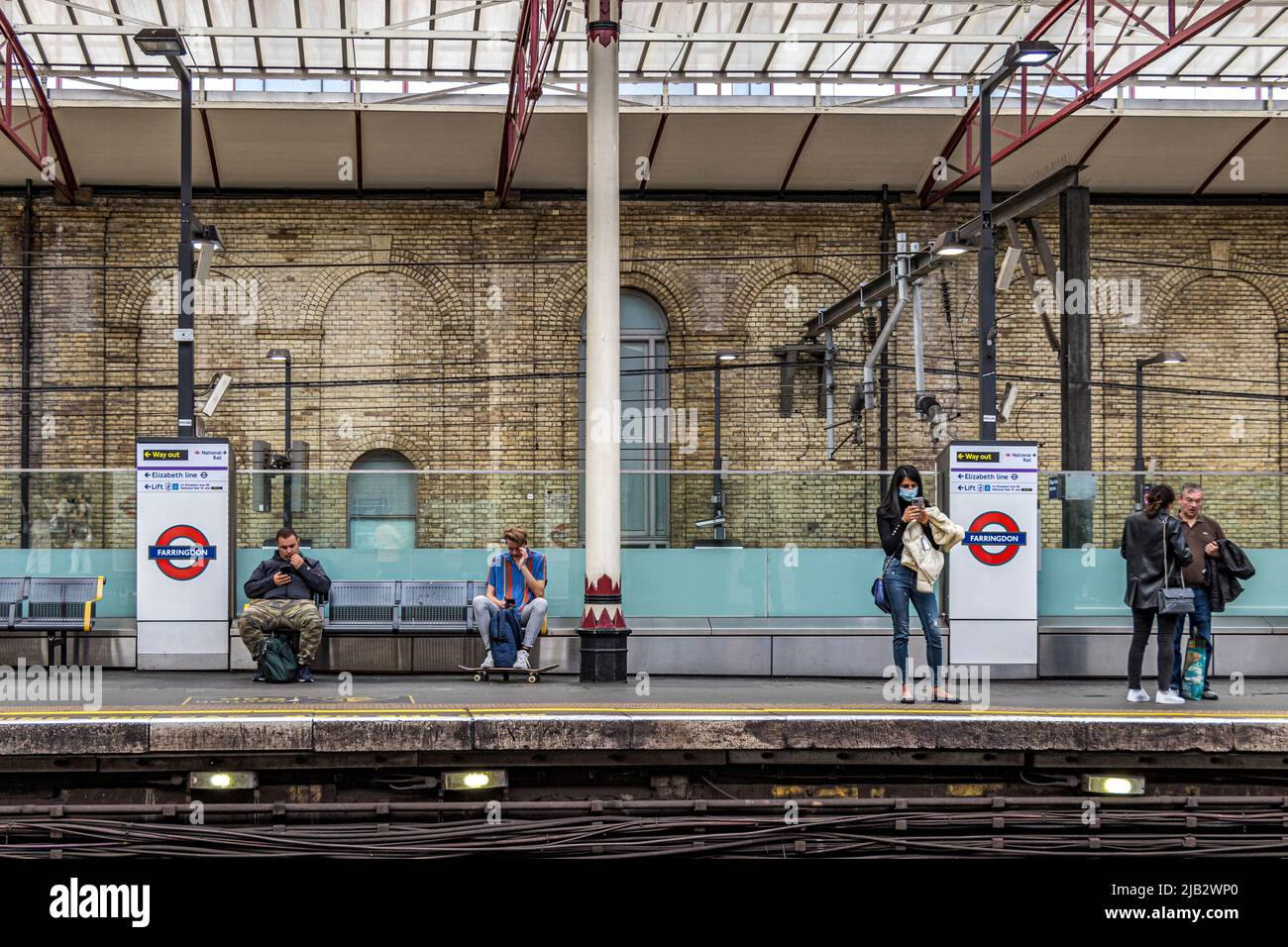 Gente esperando en la plataforma de la estación para un tren subterráneo de Londres en la estación de metro Farringdon, Londres, EC1 Foto de stock