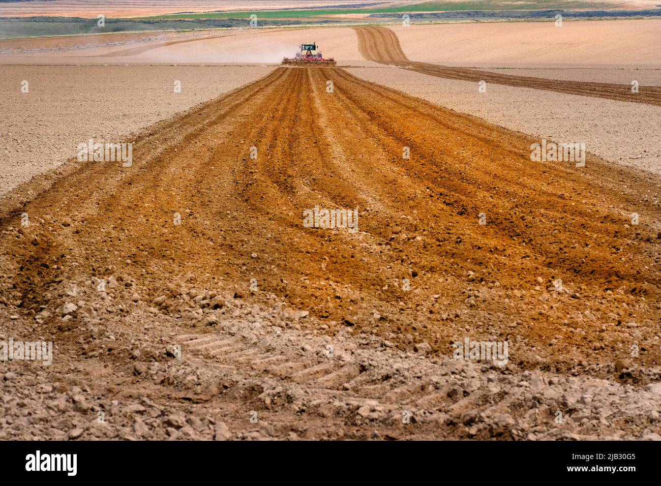 El granjero que araba el campo en la granja en la operación agrícola se enforra con el equipo del tractor Foto de stock