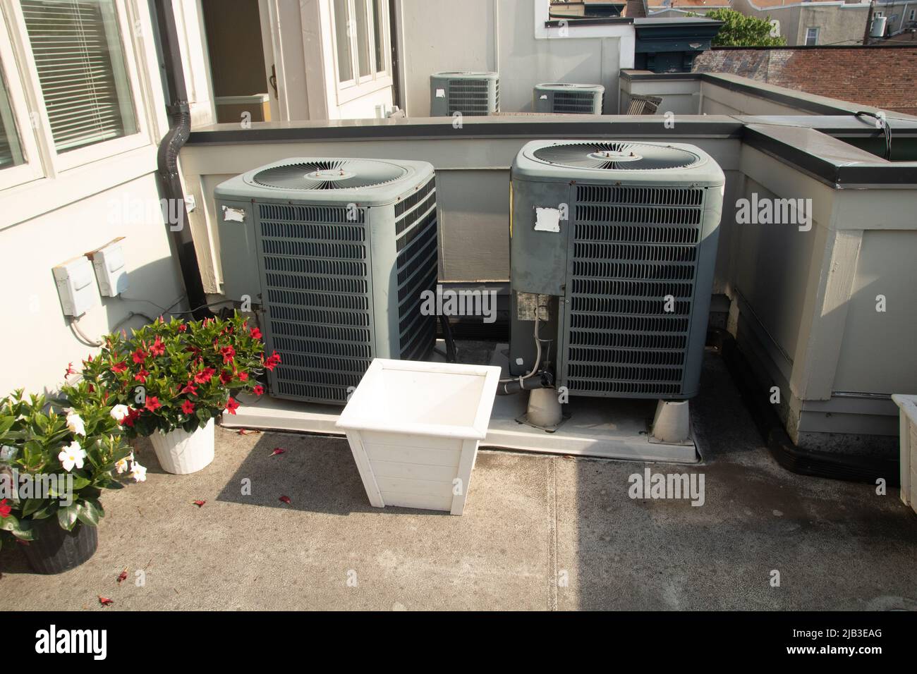 Unidades de aire acondicionado en la terraza del tejado al sol con plantas Foto de stock