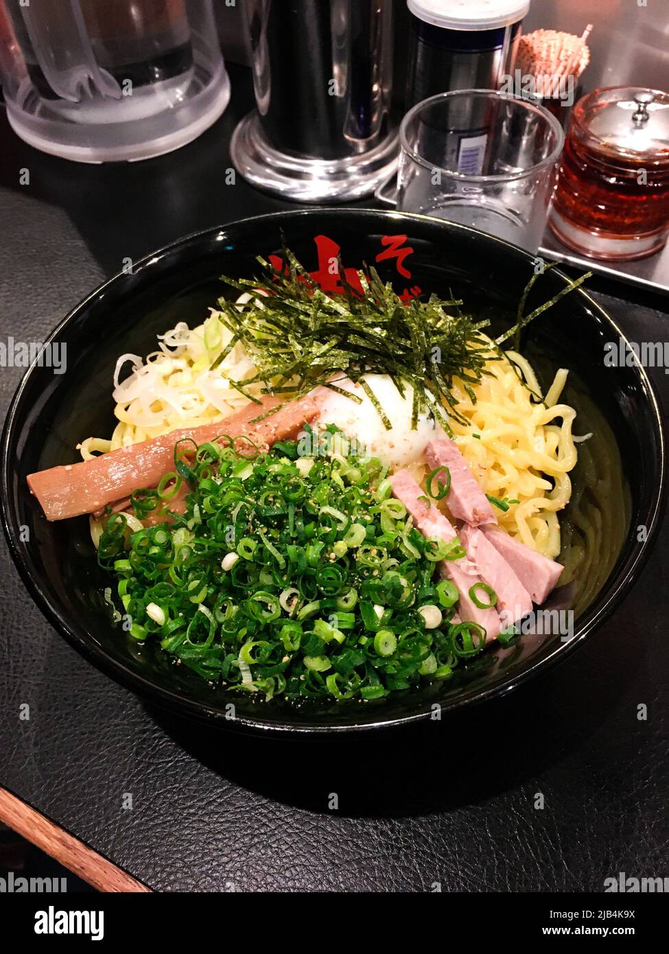 El Abura Soba (fideos de aceite) japonés, un tipo de ramen japonés con cebollas verdes picadas, jamón, menma, nori y huevo hervido (Hanujku) en la mesa del restaurante Foto de stock